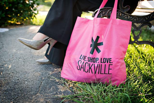 Someone sitting on a bench holding a shopping bag