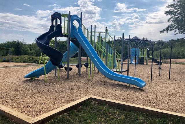 Playground surrounded by gravel with large slide. 