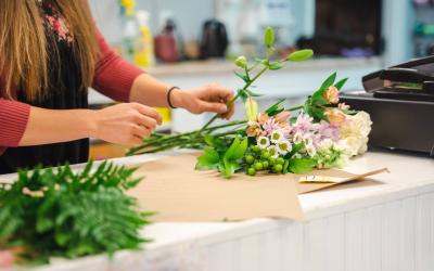 Florist arranging a flower arrangement on a table.