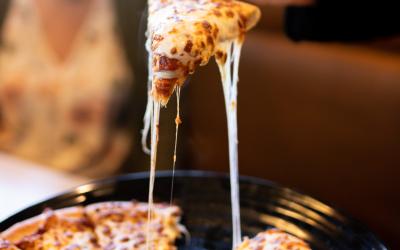 A cheesy slice of pizza being pulled out of a fresh pizza pie.