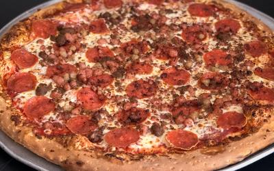 A close up of a pizza with cheese, pepperoni and hamburger crumble.
