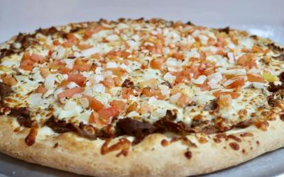 A close-up of a cheesy pizza with tomatoes and white onions.