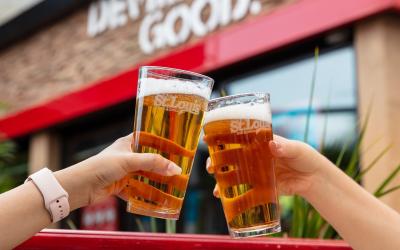Two people clinking their beers together outside of St. Louis on the patio