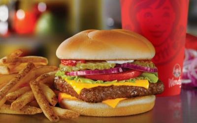 A burger, fries and soft drink in a Wendy's cup on a counter.