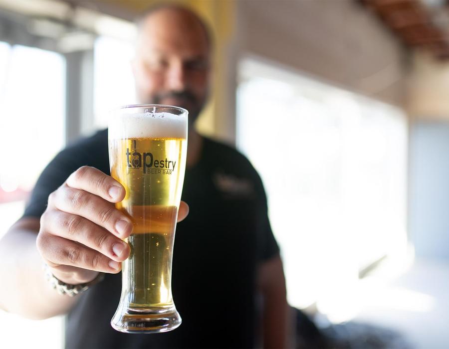 Ian Smith holding a beer at TAPestry Beer Bar